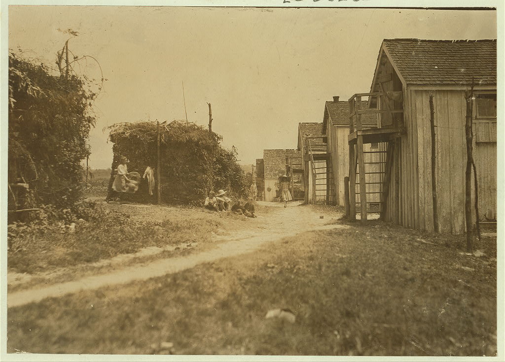 "Shanties and cooking shacks on berry farm of Bottomley's, near Baltimore. Md. At times, four families live in one shanty: three families is the rule--two rooms. (See report of July 10, 1909.)", 1909 - Lewis Hine - <i>Library of Congress</i>