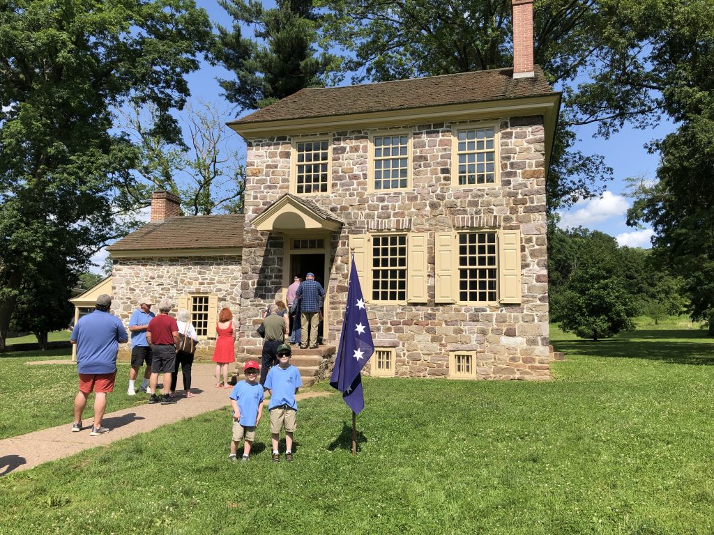 The boys stand with General Washington's headquarters flag outside of the Isaac Potts House. General Washington used the structure as his headquarters that winter. - Photo by the Author