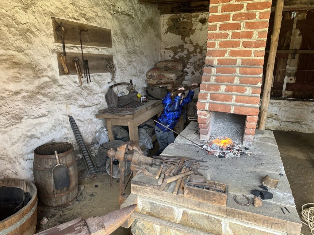 Followed by helping with the blacksmith demo! Isaac works the bellows. - <i>Photo by the author</i>